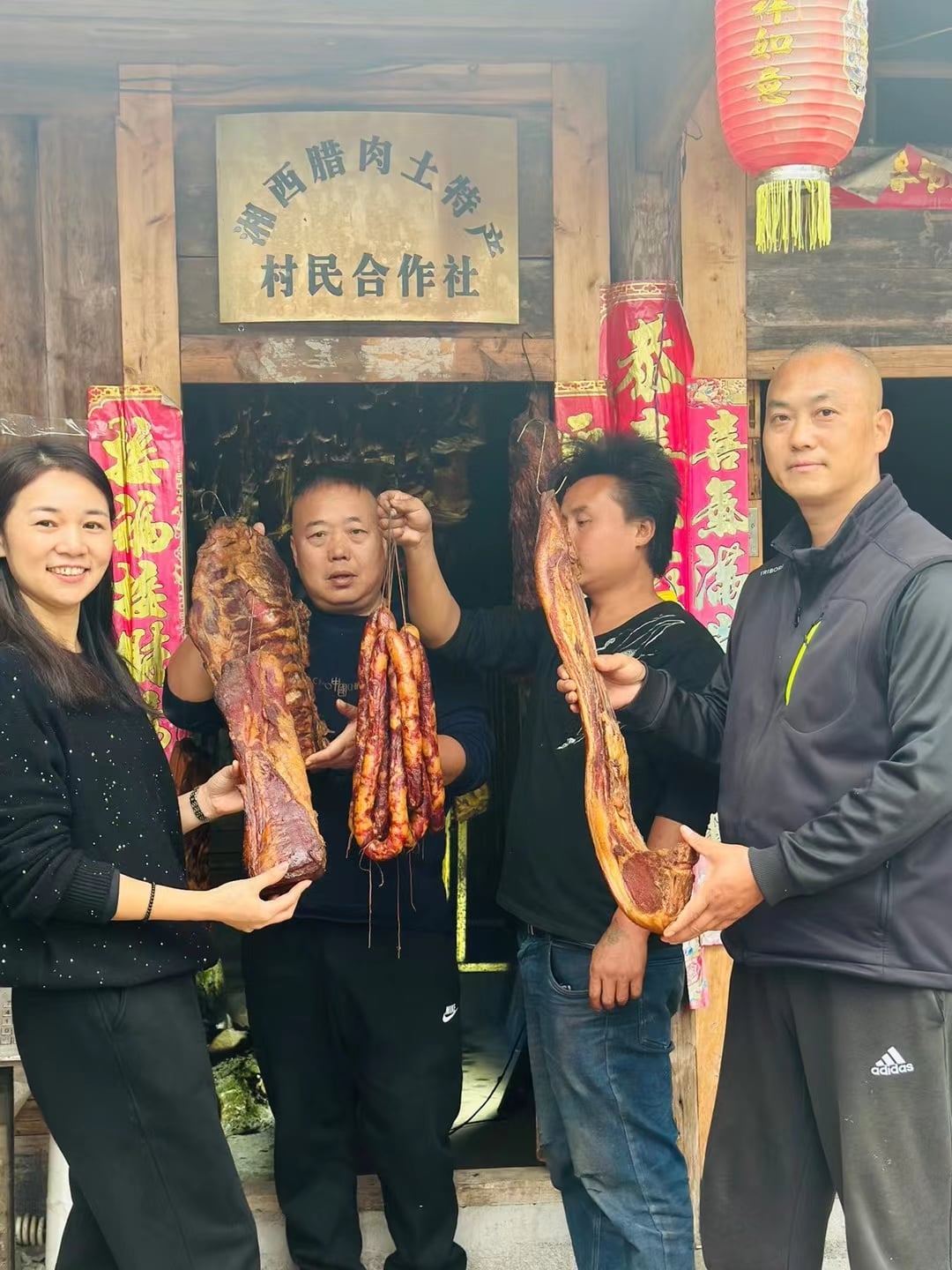 几个人在村民合作社门口展示腊肉