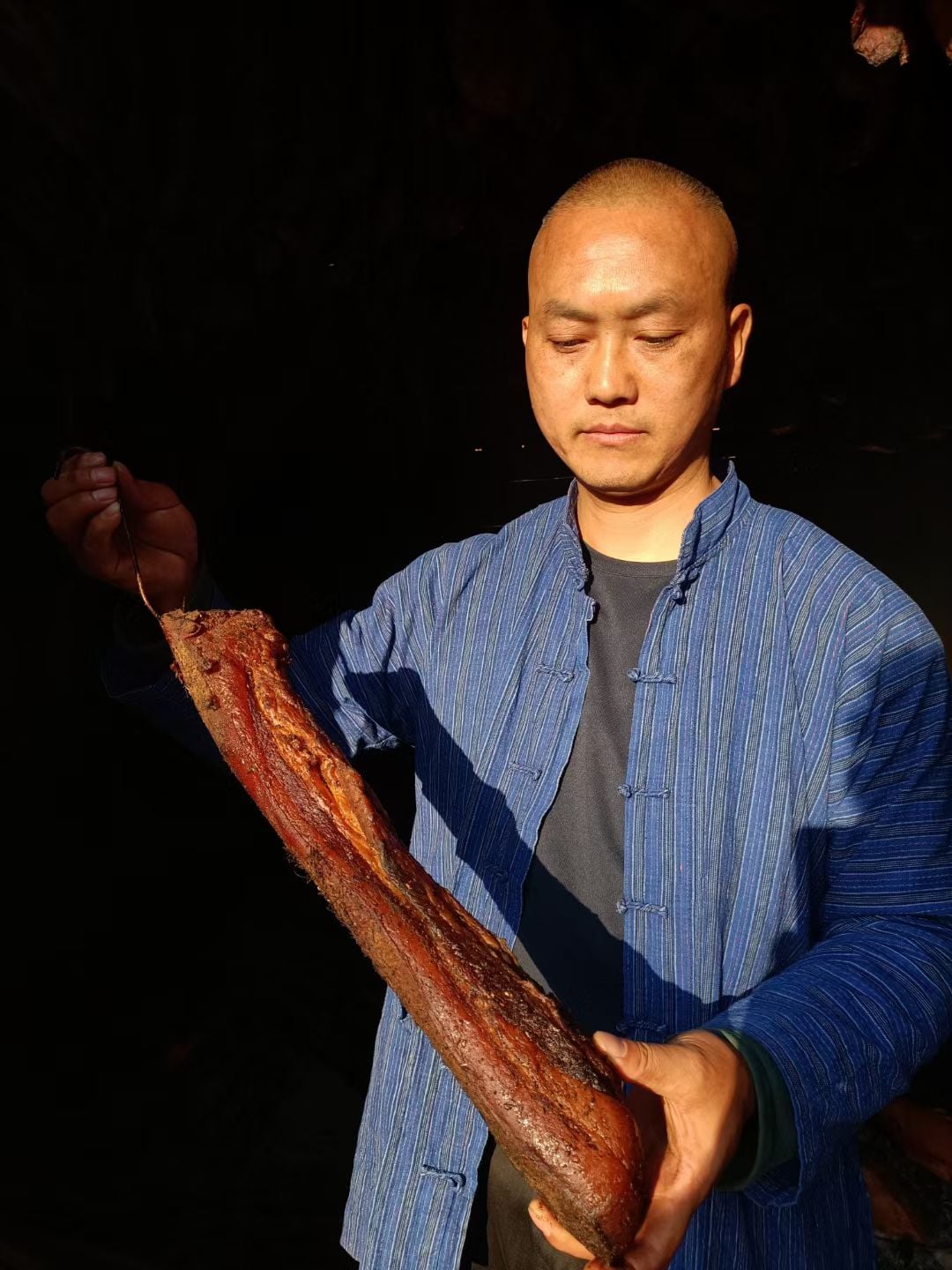 双手捧着一整块熏好的腊肉